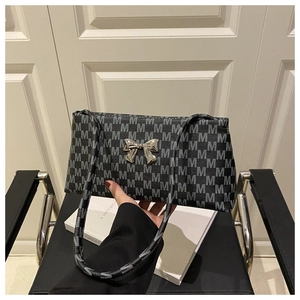 Macro detail of retro monogram printed shoulder bag with silver metallic bow accent