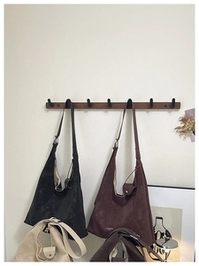 Détail de sacs cabas en cuir mat en plusieurs couleurs suspendus à un crochet