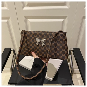 Detail of vintage brown monogram bag with silver bow buckle and letter M print
