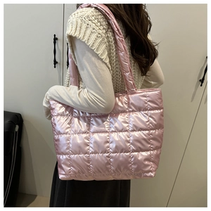Detail of metallic pink quilted tote bag showing padded texture and stitching on shoulder