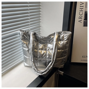 Detailed view of silver quilted metallic tote bag placed against a minimalist window