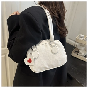 Detail of white lychee leather shoulder bag with a red heart charm on black blazer