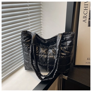 Close-up of black quilted puffer tote bag featuring glossy waterproof nylon material