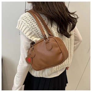 Close-up of brown litchi pattern leather shoulder bag with a red heart pendant charm