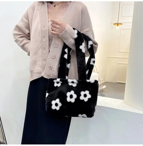 Detail of a black plush handbag featuring white flower patterns and soft faux fur texture