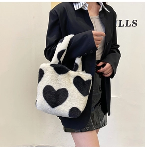 Détail du sac à main en peluche avec motif de cœur noir et texture douce en fausse fourrure