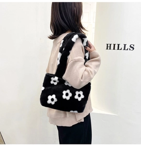 Detail of black plush shoulder bag featuring a white flower pattern and wide strap