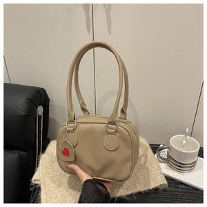 Close-up of lychee grain shoulder bag with long handles and a red heart charm