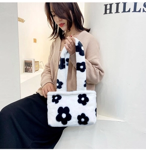 Detail shot of white plush tote bag with large black floral patterns on a fluffy texture