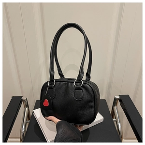 Close-up of black lychee grain leather handbag with silver hardware and red heart charm