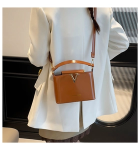 Detailed back view of a caramel leather crossbody bag with metallic V logo on a model
