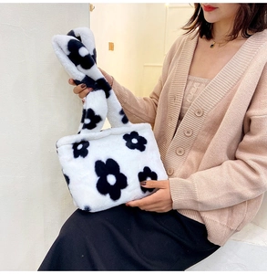 Detailed texture of white plush tote bag with black floral patterns held by a model