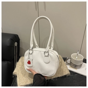 Detail of white lychee leather handbag with a red heart pendant and silver hardware