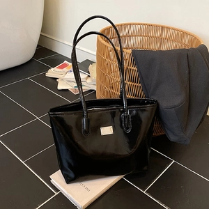Large black patent leather tote bag with silver metal plate and minimalist design