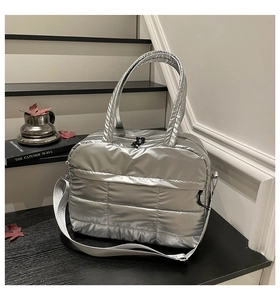 Detail of silver quilted puffer bag with metallic finish and adjustable strap