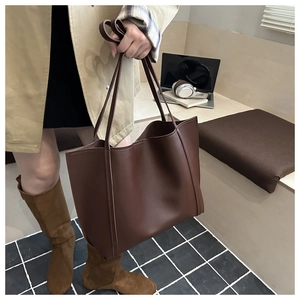 Large dark brown tote bag shown with a laptop and books for a professional commute look