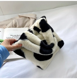 Vue détaillée du sac à main cœur en peluche avec texture douce à motif vache noir et blanc