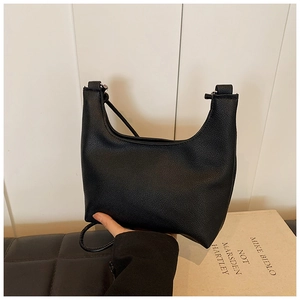 Close-up of black lychee grain texture on a minimalist crescent-shaped shoulder bag