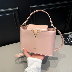 Elegant light pink leather handbag with gold V logo and versatile crossbody shoulder strap