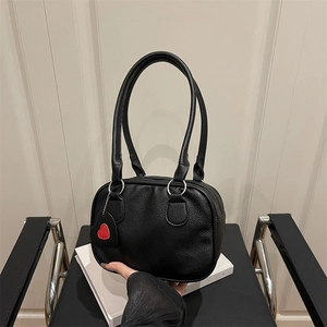 Black litchi pattern bowling handbag with red heart charm on minimalist white background