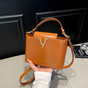 Elegant brown patent leather tote bag with gold V logo and versatile shoulder strap