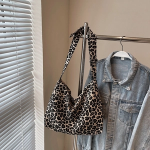 Large leopard print hobo bag with adjustable strap shown hanging next to denim jacket