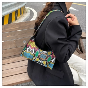 Detail of colorful snakeskin hobo bag with vibrant patchwork texture worn by model