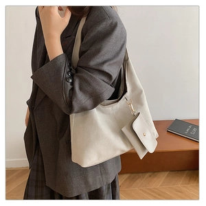 Detail view of a large beige faux suede tote bag with matching snap pouch on model