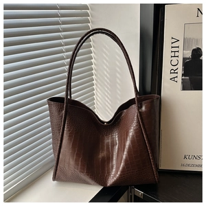 Detail of dark brown faux crocodile leather tote bag with glossy finish and thin straps
