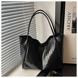 Detail of black crocodile texture tote bag with elegant shadow on glossy PU leather