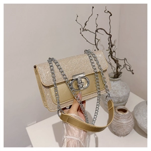 Macro detail of champagne gold shoulder bag featuring glitter texture and metal buckle lock