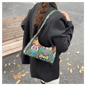 Shoulder bag detail featuring colorful snakeskin print and slim black leather strap