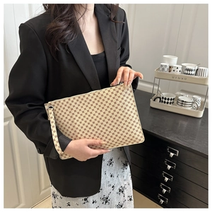 Macro view of beige envelope clutch with brown monogram pattern and wrist strap