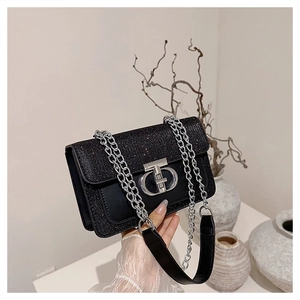 Detail of glittery textured flap and silver metal interlocking buckle on black crossbody bag