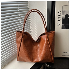 Detail shot of brown crocodile embossed tote bag with glossy texture and soft structure