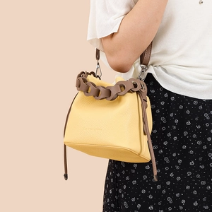 Detail of yellow lychee leather bucket bag with brown decorative chain and drawstring