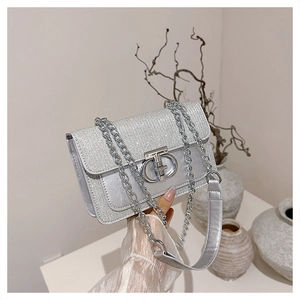 Detailed view of silver sequin bag with metallic Gancini style clasp held by model