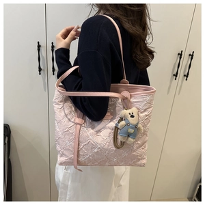 Detail of pink quilted tote bag with floral embroidery and cute bear plush charm
