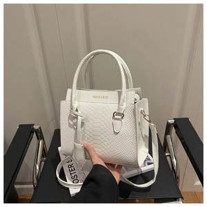 Close-up of white snakeskin texture and gold Fashion logo on a stylish handbag