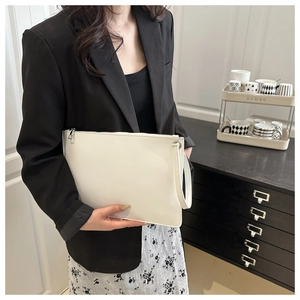 Detailed close-up of the white minimalist envelope clutch with matte leather and wrist strap