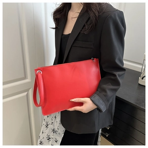 Chic red PU leather envelope clutch with top zipper and wristlet strap held by model