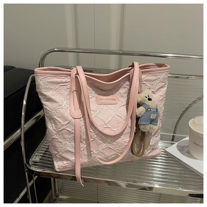 Dettaglio borsa tote rosa trapuntata con ricamo floreale e ciondolo a orsetto