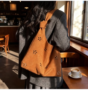 Détails du motif floral ajouré et de la bandoulière nouée sur un sac cabas en daim