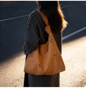 Détail du sac cabas en daim fauve avec motifs de fleurs découpés au laser et bandoulière