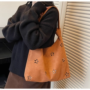 Détail de fleurs découpées au laser et bandoulière nouée sur un cabas en daim orange