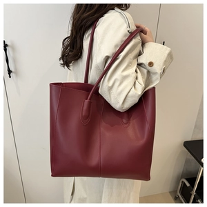 Close-up of deep red tote bag featuring matte leather texture and decorative stitching