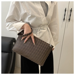 Close-up of brown geometric pattern monogram envelope bag with wristlet strap and zipper