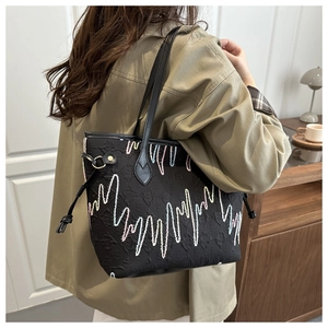 Lifestyle view of large black tote bag with rainbow wave embroidery and leather straps