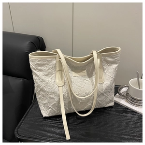 Detailed macro view of cream-white tote bag with unique embossed wrinkled fabric texture