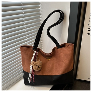 Détail d'un sac cabas bicolore en daim marron avec un joli pendentif ours en peluche doux